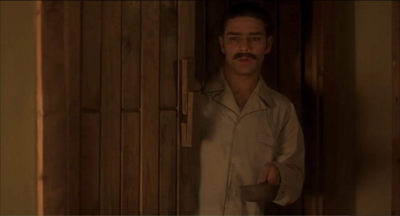 Like Water for Chocolate (1992) movie still: medium — An interior space features vertical wooden paneling lining the walls and a single doorway. A…