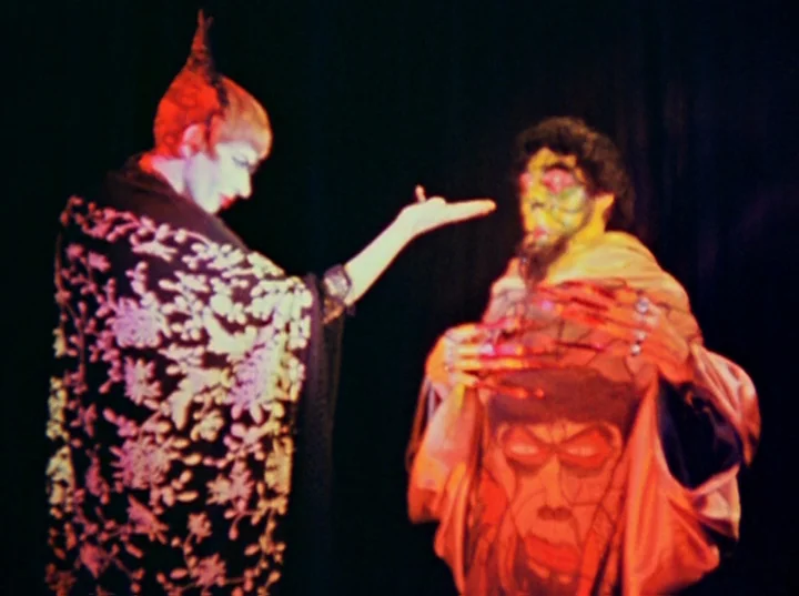 Inauguration of the Pleasure Dome (1954) movie still: medium — A dark theatrical stage features two performers standing before a solid black…