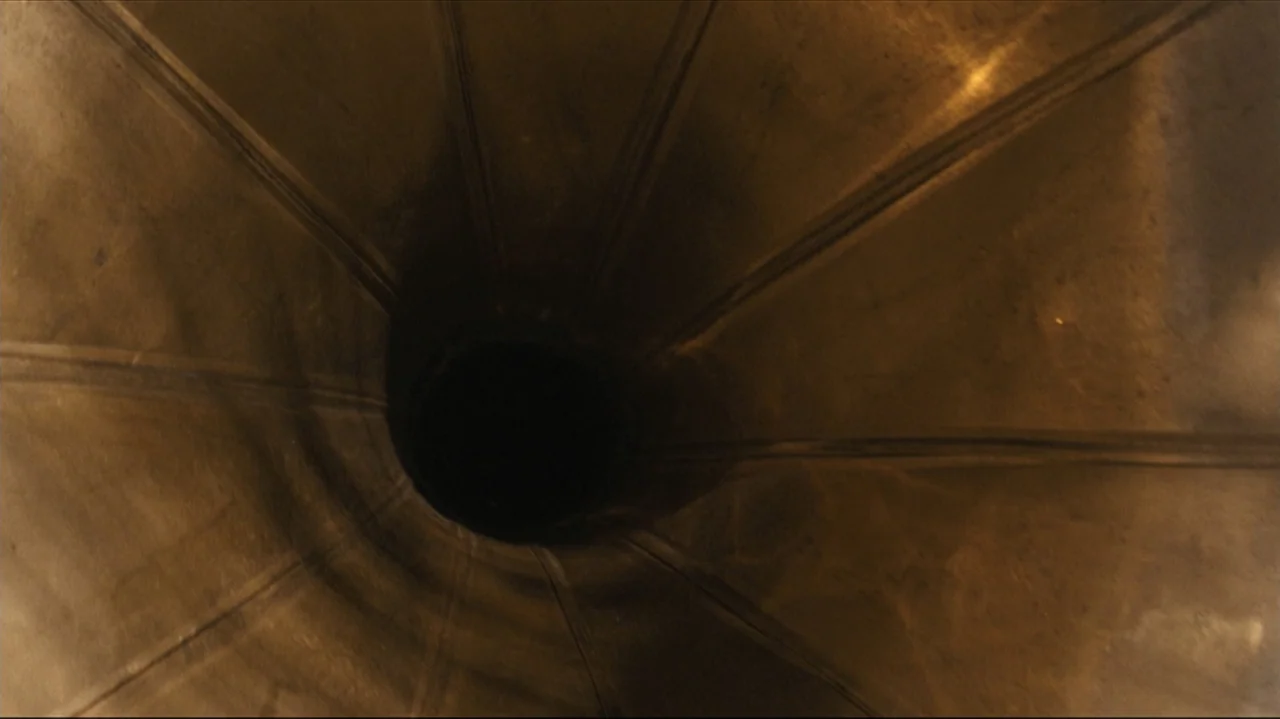 Shadows in the Sun (2005) movie still: closeup — The interior of a metallic phonograph horn features radiating ridges leading to a dark center. The…