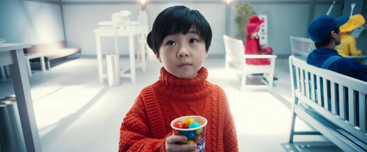 Prisoners of the Ghostland (2021) movie still: medium — A brightly lit waiting area features white furniture and neutral walls. A young child in an…