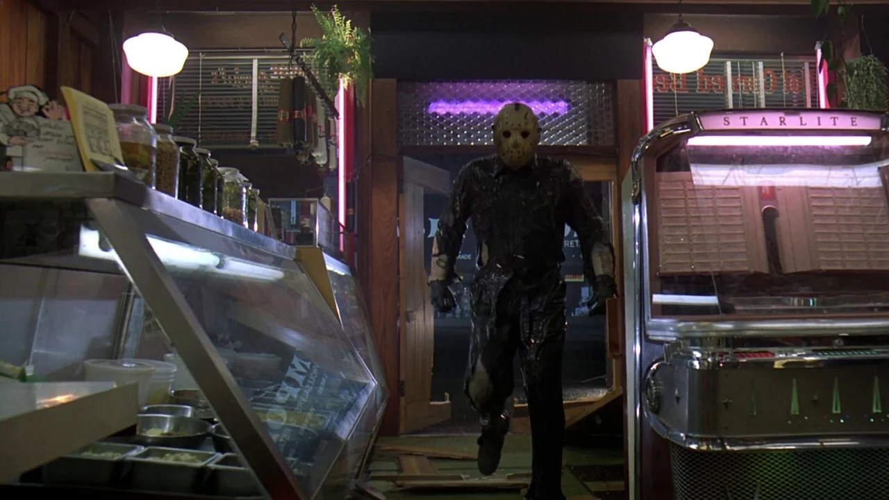 Friday the 13th Part VIII: Jason Takes Manhattan (1989) movie still: fullbody — A dimly lit diner features a glass display case and an old jukebox…