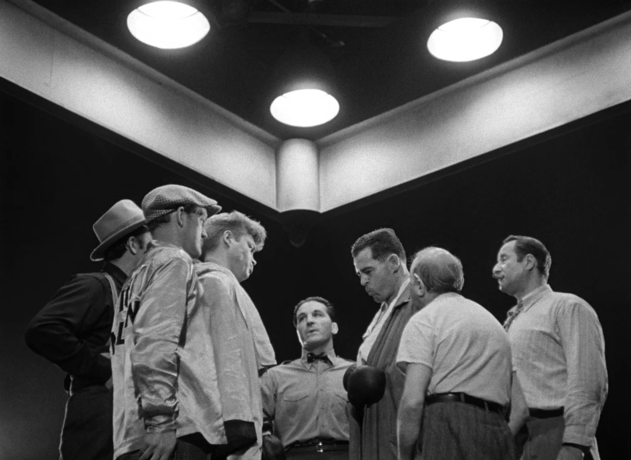The Set-Up (1949) movie still: medium — A group of men in a dimly lit locker room stand in a tight circle. They appear to be in mid-conversation…