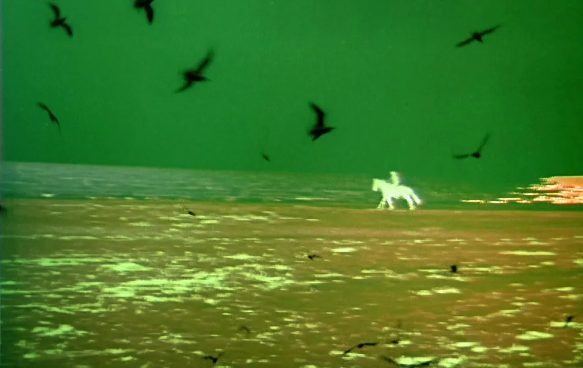 The Girl on a Motorcycle (1968) movie still: wide — A vast, flat, and sparse field is bathed in a distinct green color tone. A single bright,…