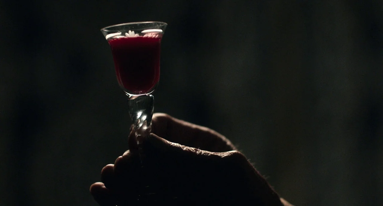Only Lovers Left Alive (2013) movie still: closeup — A close view shows a glass filled with deep red liquid against a dark backdrop. A weathered…