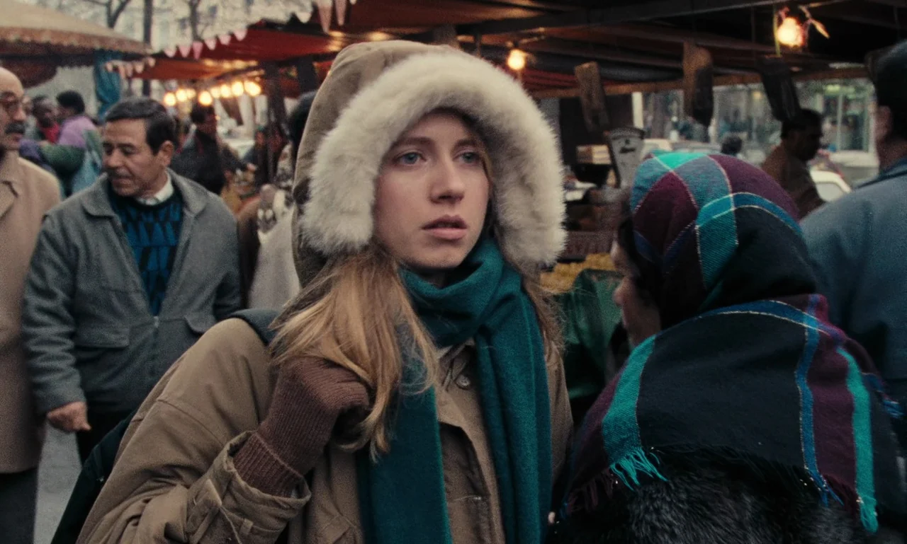 A Tale of Winter (1992) movie still: medium — A crowded winter market scene featuring various stalls and shoppers in winter attire. A young woman…