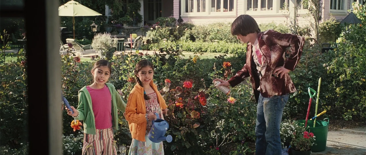 Yours, Mine & Ours (2005) movie still: fullbody — A sunny residential backyard features a rose bush and a suburban house. Two young girls stand…