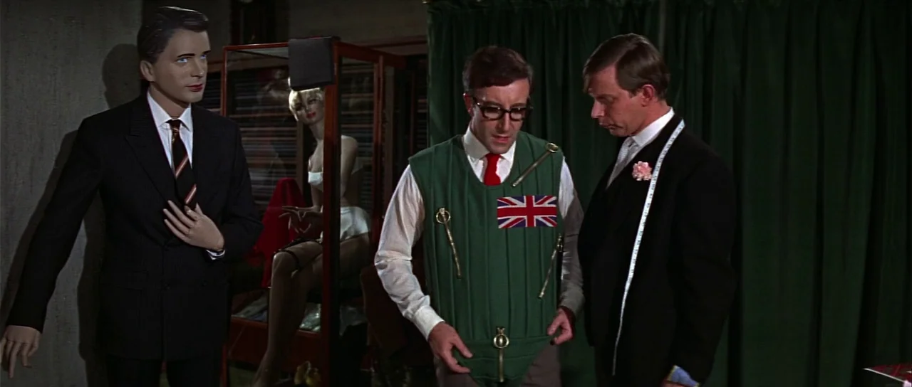 Casino Royale (1967) (1967) movie still: medium — A tailor shop interior features mannequins and dark curtains. A customer stands examining a green…