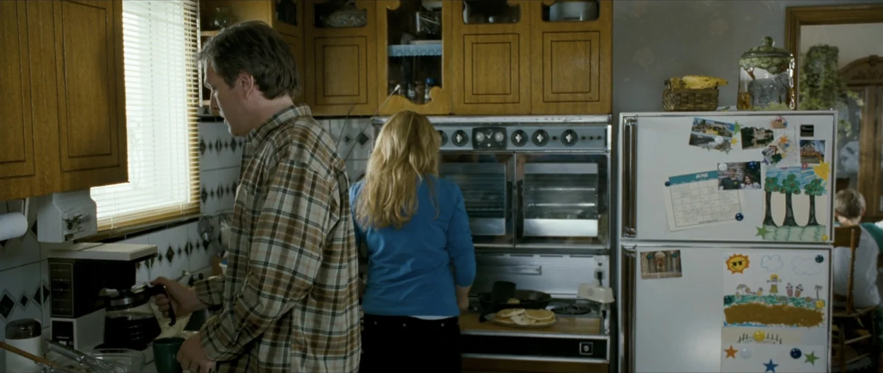 The Haunting in Connecticut (2009) movie still: medium — A residential room featuring wood cabinets, a double oven, and a white refrigerator covered…