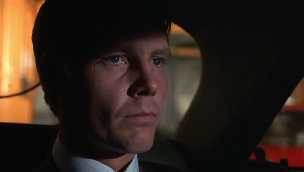 Performance (1970) movie still: closeup — Inside a dark vehicle at night with soft light hitting the driver's face. A man sits behind the steering…