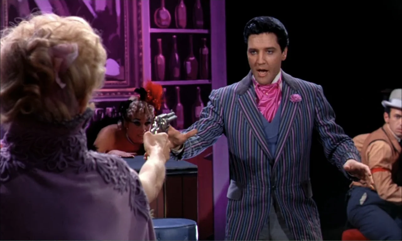 Frankie and Johnny (1966) movie still: medium — A theatrical saloon set with purple-lit bottle displays and dark wooden architectural features. A…