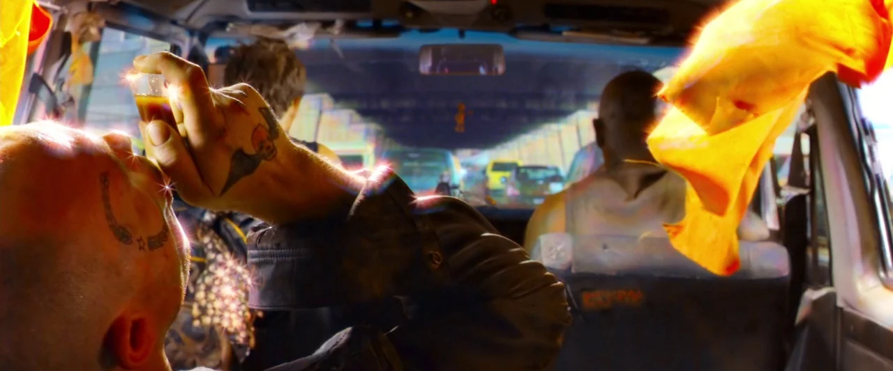Dredd (2012) movie still: medium — Inside a vehicle traveling along a highway with blurry traffic visible through the windshield. A man with a hand…