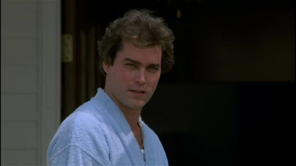 Goodfellas (1990) movie still: closeup — A man stands in an open doorway of a house during the day. He looks directly toward the camera with a…