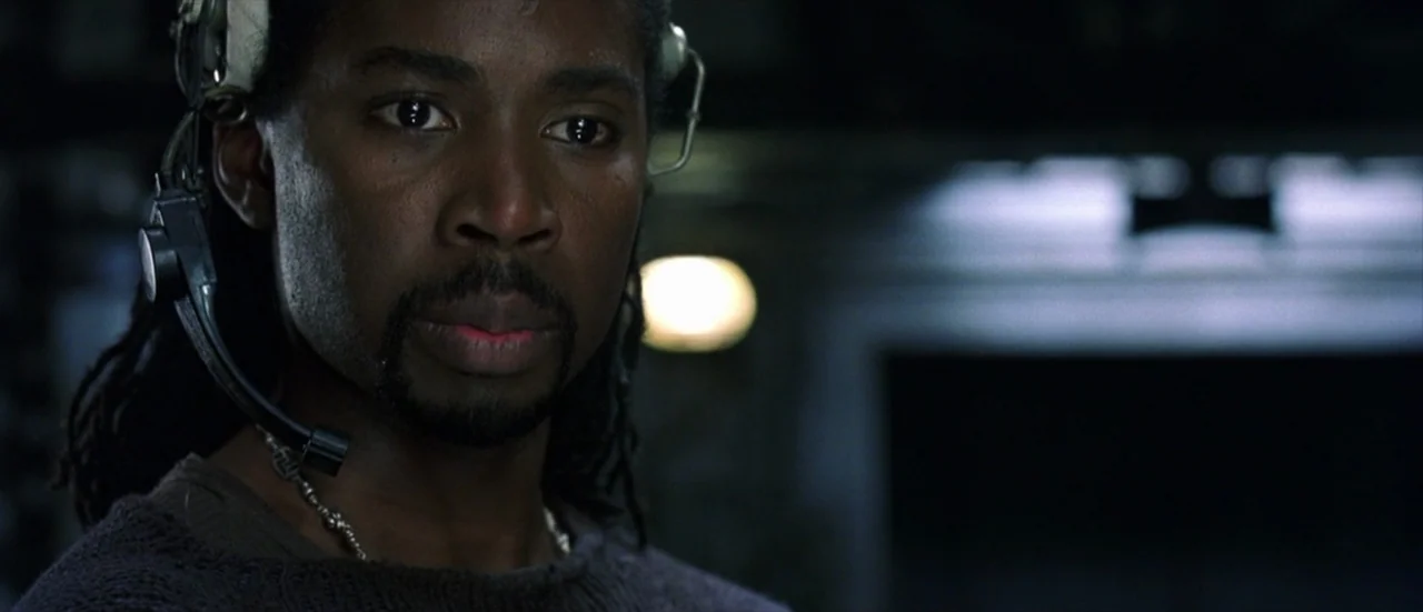 The Matrix Revolutions (2003) movie still: closeup — A dark, industrial submarine interior with metallic surfaces and dim ambient lighting. A man…