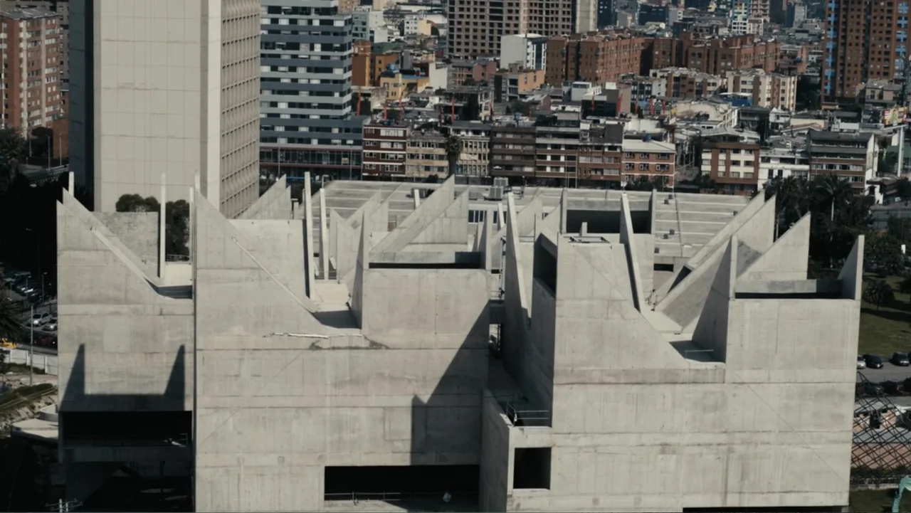 Victoria's Secret: The Tour '23 (2023) movie still: establishing — A massive, Brutalist-style concrete building features sharp angular roofs and…