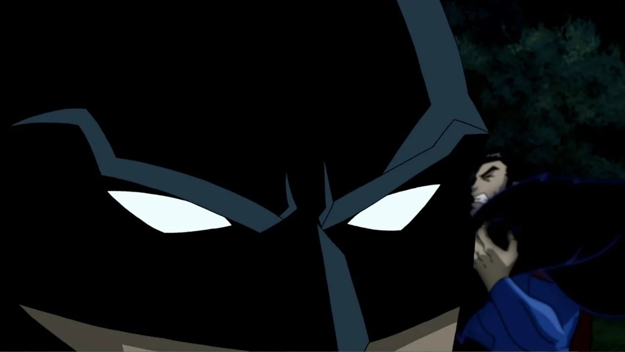 Superman/Batman: Public Enemies (2009) movie still: closeup — A dark outdoor area at night with trees faintly visible in the background. Batman…