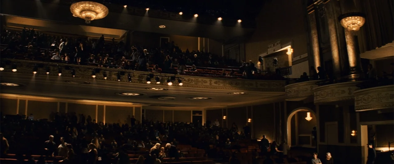 Now You See Me (2013) movie still: wide — A spacious multi-level theater interior features ornate moldings and tiered seating for a crowd. People…