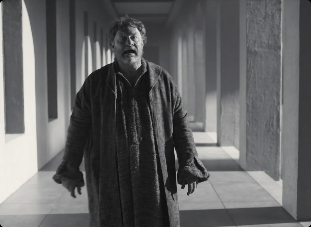 The Tragedy of Macbeth (2021) movie still: fullbody — A long colonnade hall with recurring stone pillars creating striped shadow patterns on the…