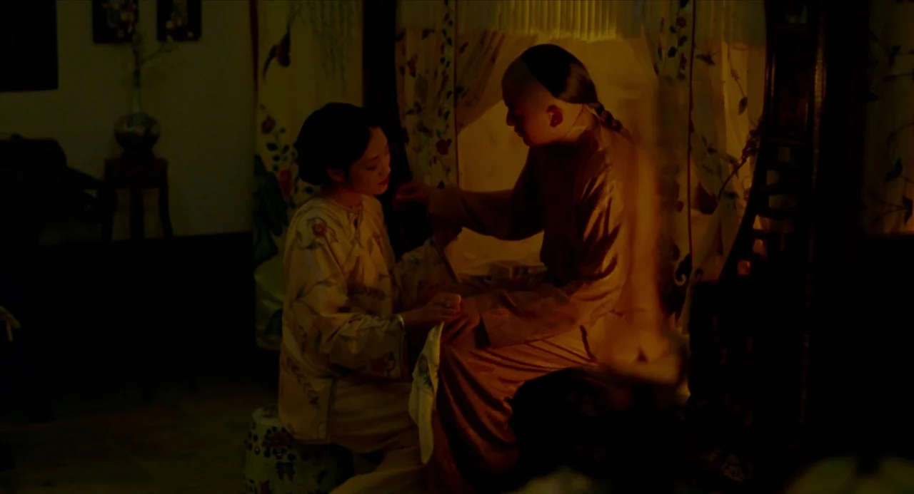 Flowers of Shanghai (1998) movie still: medium — A dimly lit room features traditional furniture including a wooden bed frame with curtains. A woman…