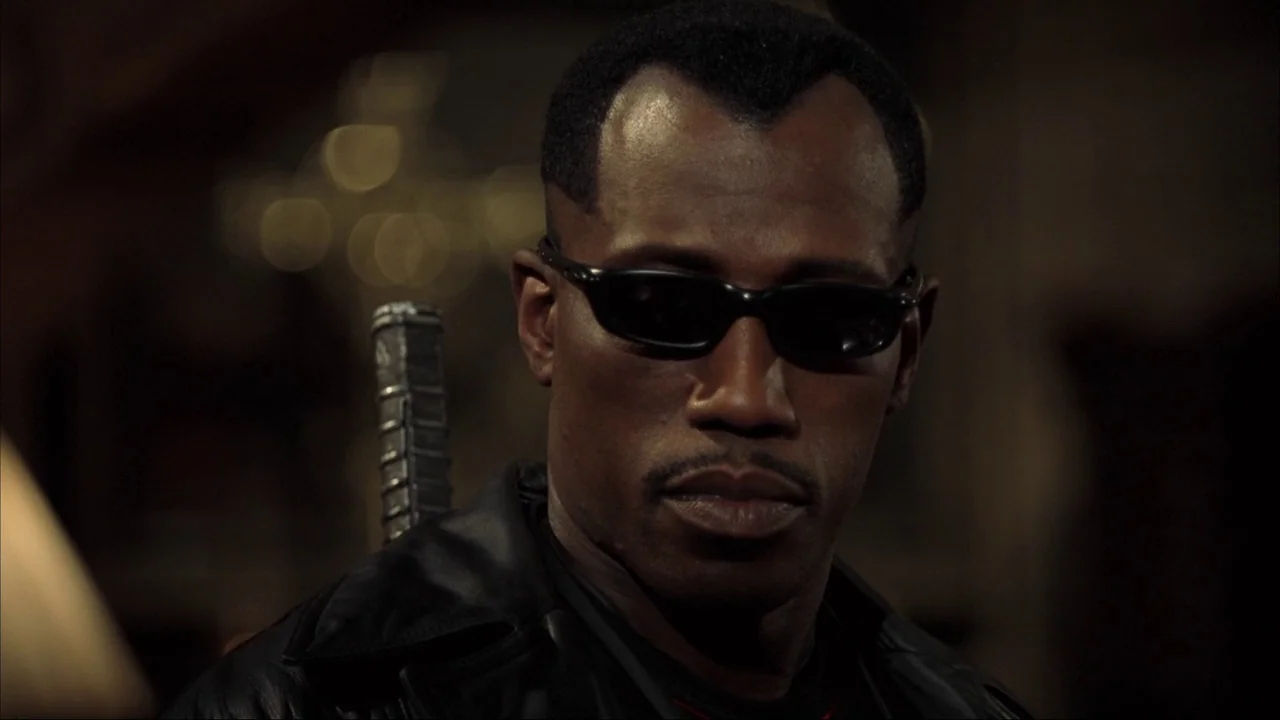 Blade II (2002) movie still: closeup — A dark, dimly lit environment features a man in a black leather jacket. The character stares ahead while the…