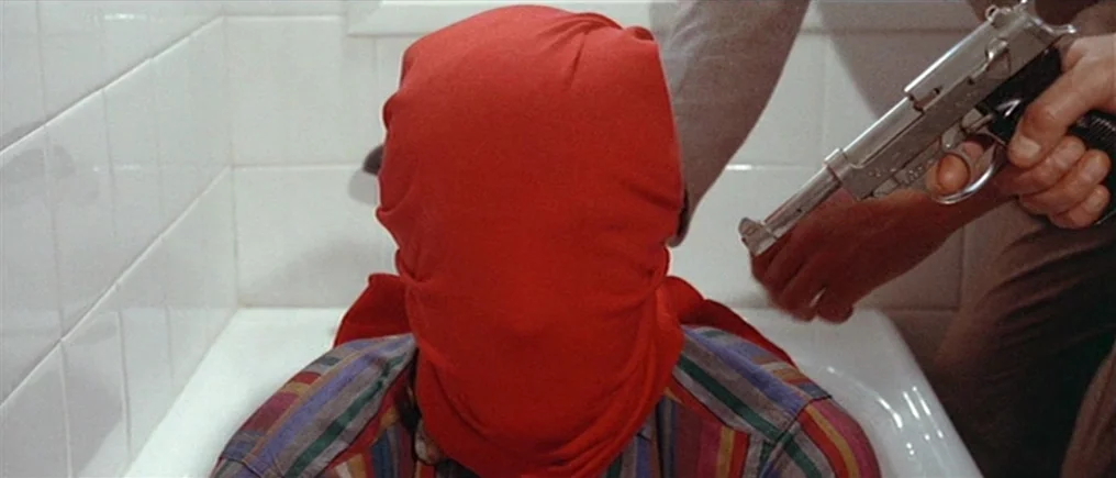 Pierrot Le Fou (Crazy Pete) (1965) movie still: medium — A person wearing a bright red hood sits inside a white porcelain bathtub. A second person…