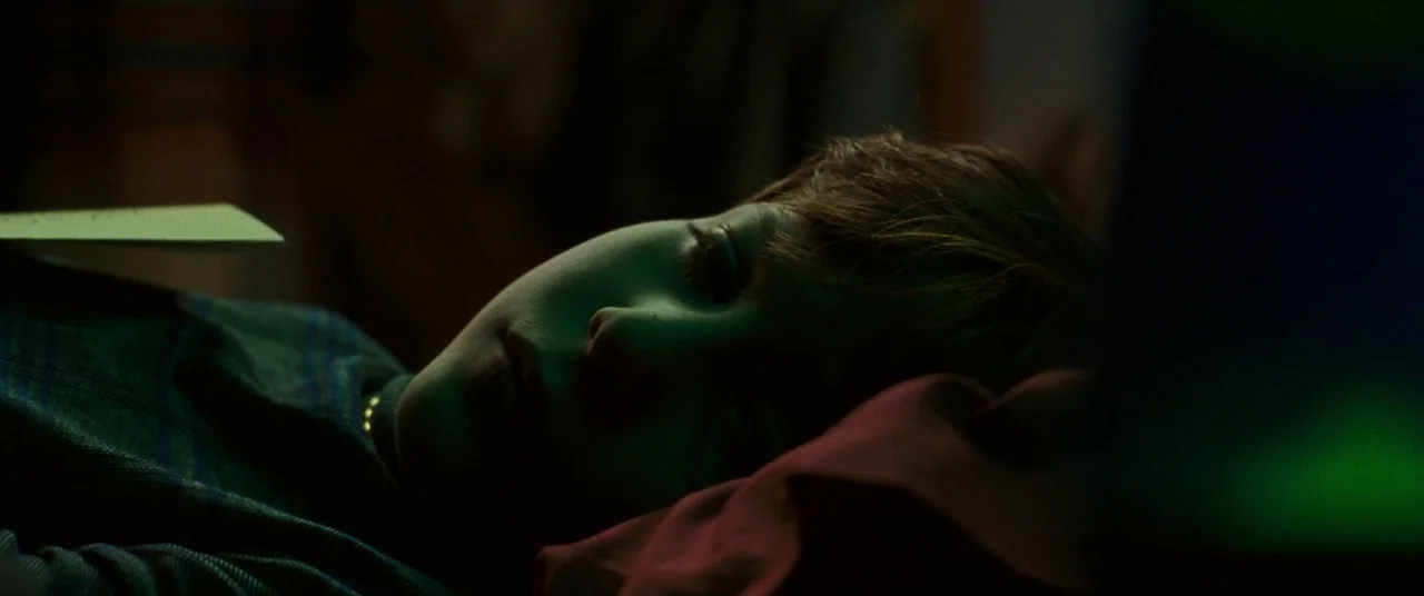 The Death and Life of John F. Donovan (2018) movie still: closeup — A dark, dimly lit space features a person lying in bed at night. The face is…