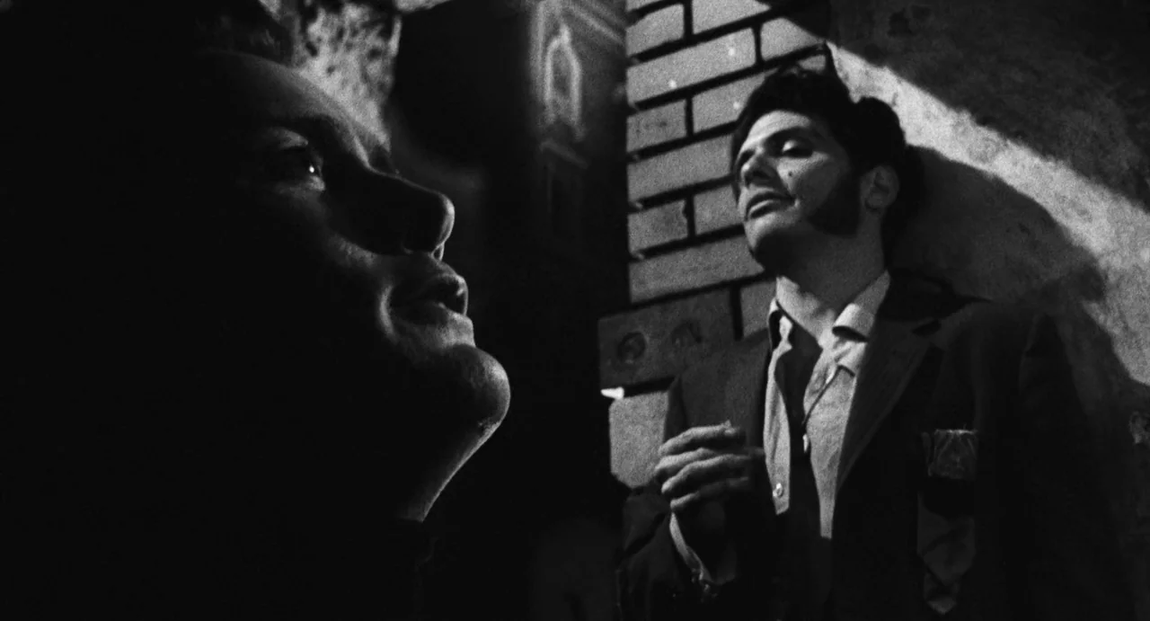 The Incident (1967) movie still: medium — Two men are positioned in front of a brick structure at night. The high-contrast lighting emphasizes the…
