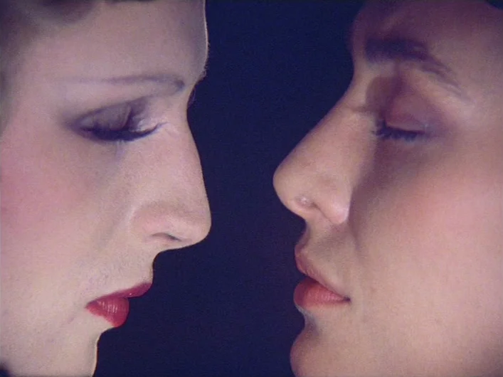 The Death of Maria Malibran (1972) movie still: closeup — Two faces in profile are positioned closely against a black, featureless background. Both…