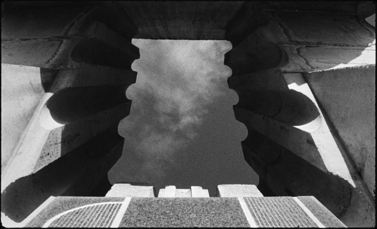 Last and First Men (2020) movie still: establishing — A stone monument features tall, fluted columns surrounding a central opening toward the sky.…