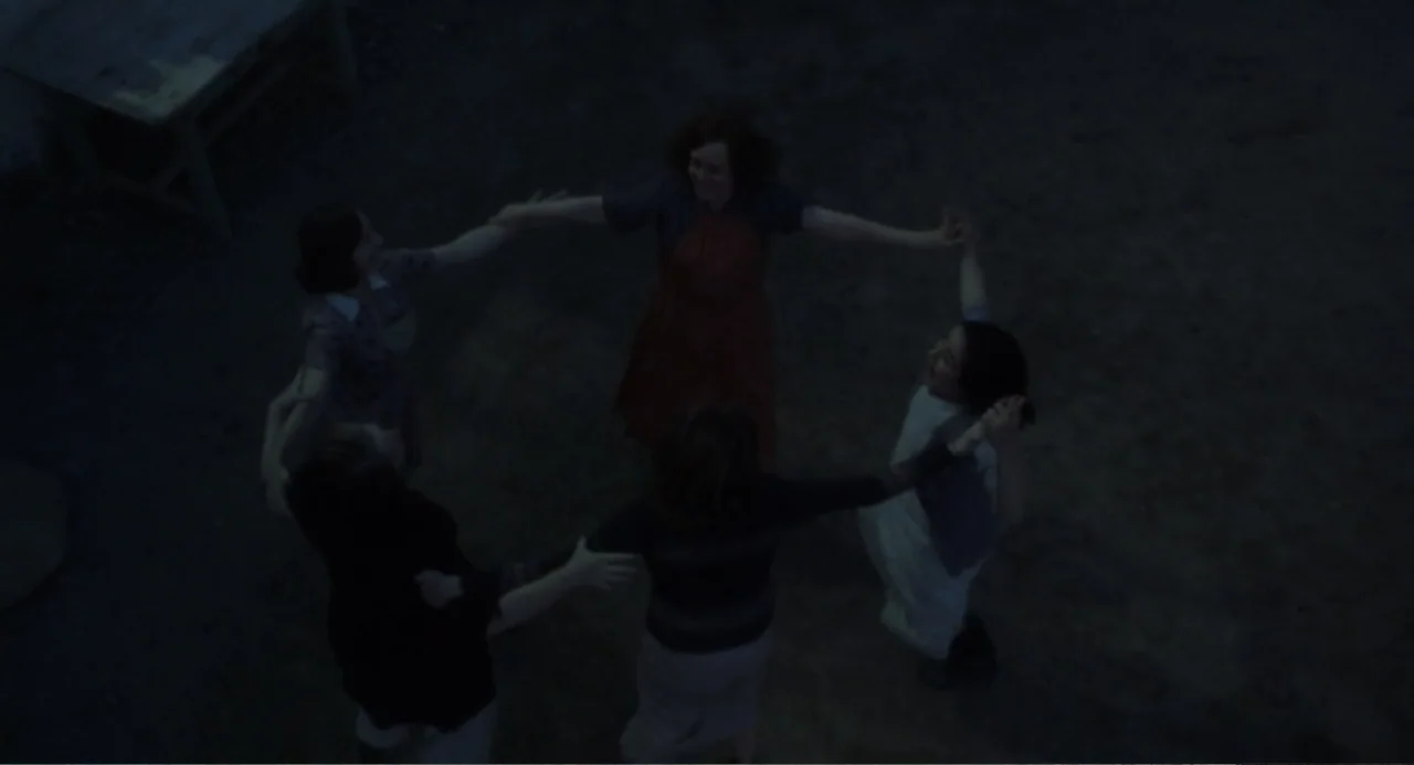 Dancing at Lughnasa (1998) movie still: wide — Five women stand in a circle on flat dirt ground under dim night conditions. They hold hands and face…