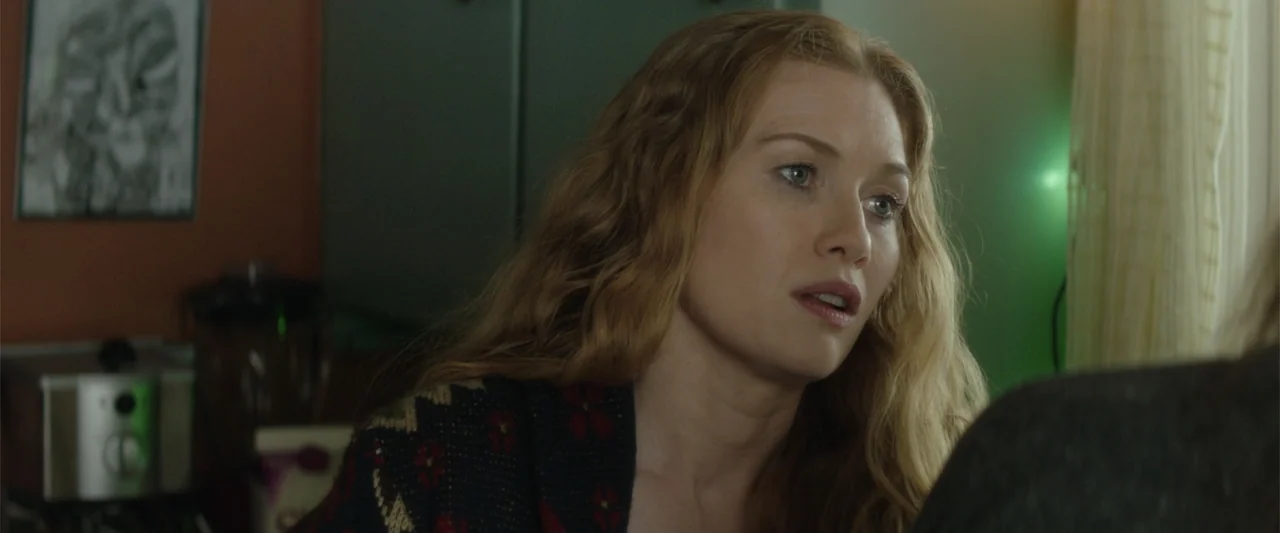 If I Stay (2014) movie still: closeup — A domestic interior with dark walls and soft indoor lighting at night. A woman with wavy hair looks toward…