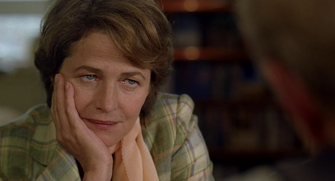 Swimming Pool (2003) movie still: closeup — A woman sits in a room with blurred shelves visible in the background. The woman leans her cheek against…