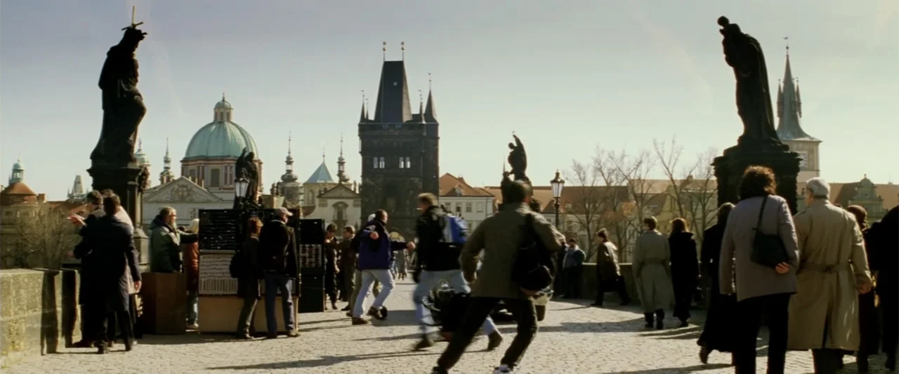 xXx (2002) movie still: wide — A historic stone bridge features ornate statues and distant European architecture under a clear sky. Multiple…