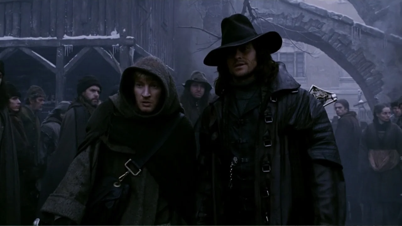 Van Helsing (2004) movie still: medium — A snowy, crowded village marketplace features rough-hewn wooden architecture and an arched stone gateway.…