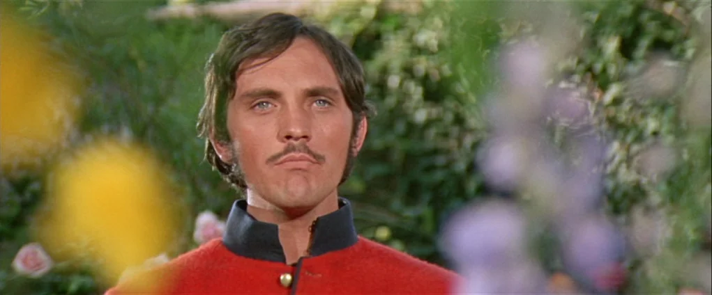 Far from the Madding Crowd (1967) movie still: medium — A man in a red military uniform stands amidst a blurred lush green garden. The subject looks…
