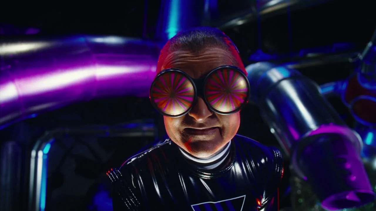 Charlie and The Chocolate Factory (2005) movie still: closeup — A dark industrial space filled with large metallic pipes glowing with purple and…
