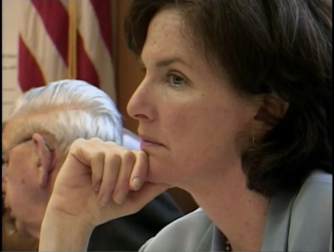 A Rape in a Small Town: The Florence Holway Story (2005) movie still: closeup — A professional setting with wood-paneled walls and an American flag…