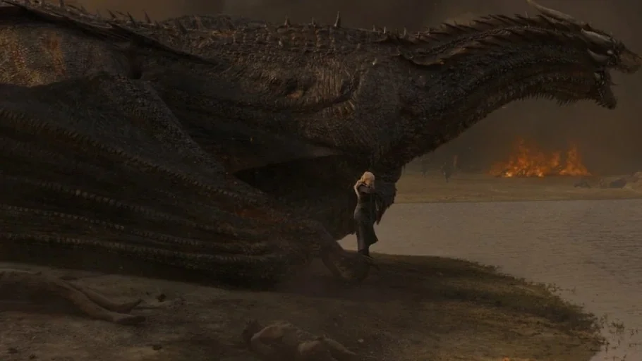 Game of Thrones (2017) movie still: wide — A dark riverbank under a smoky, ash-filled sky with fires burning in the distance. A woman stands next to…