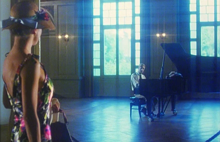 Lili Marleen (1981) movie still: fullbody — A spacious room with high ceilings features large windows and hardwood floors. A woman watches a man…