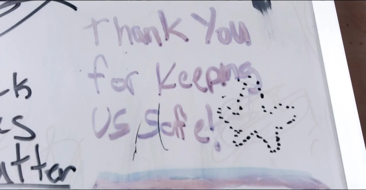 The Devil Is Busy (2024) movie still: closeup — A white board contains handwritten purple text and a black dotted star drawing. The text explicitly…