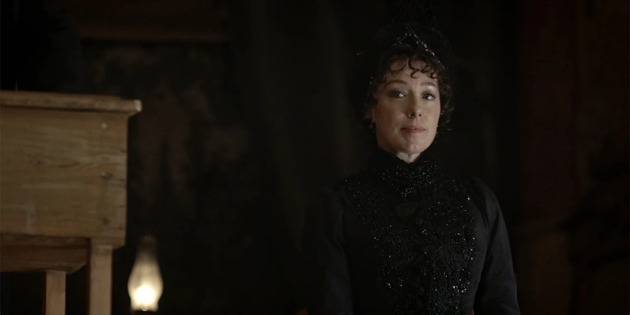 Deadwood: The Movie (2019) movie still: medium — A dimly lit Victorian interior features dark wooden walls and a period-appropriate oil lamp. A…