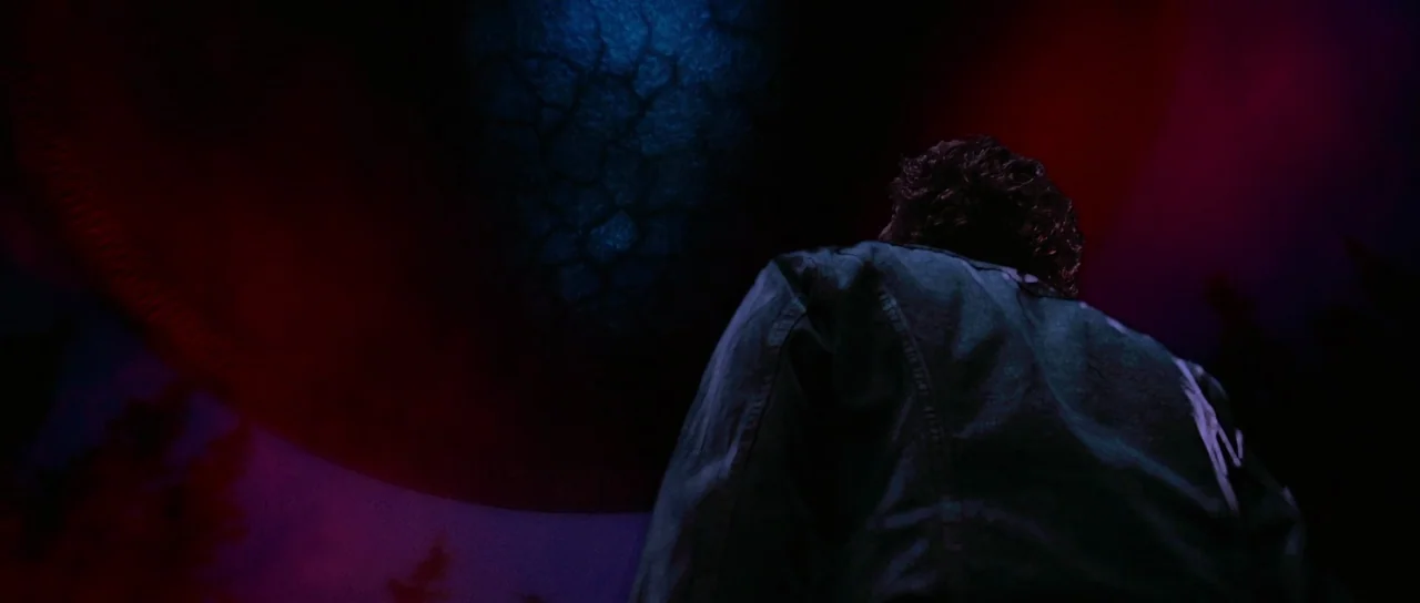 Fire In The Sky (1993) movie still: medium — An open landscape at night features a massive, cracked, bioluminescent orb hovering above. A man stands…