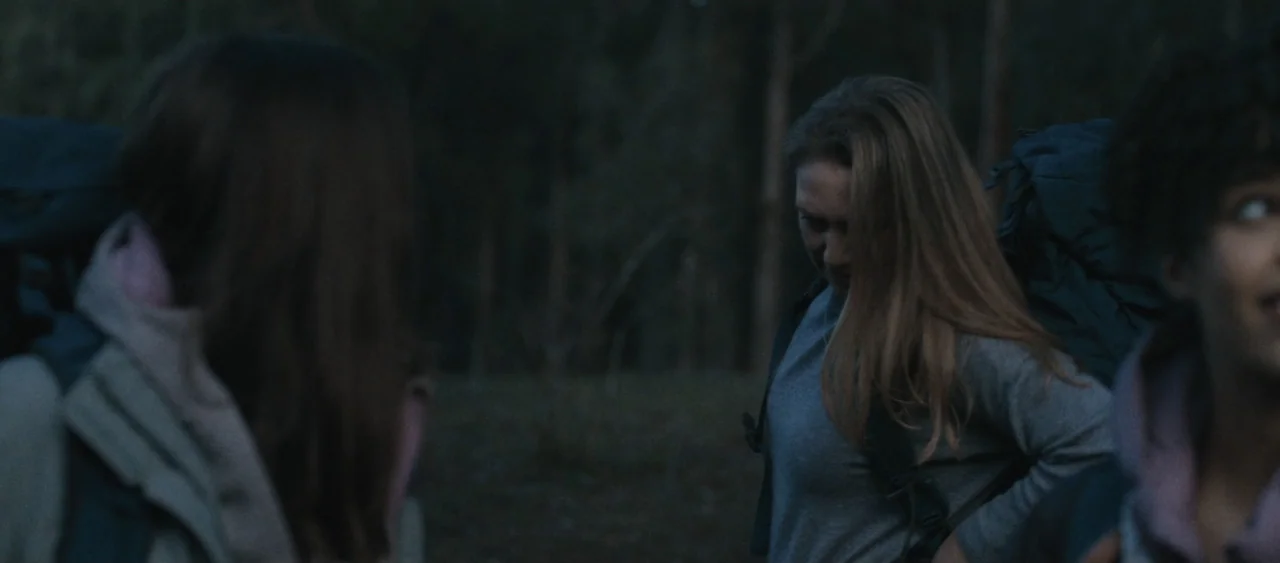 Force of Nature: The Dry 2 (2024) movie still: medium — A dark outdoor wooded area at night with trees faintly visible in the background. Three…