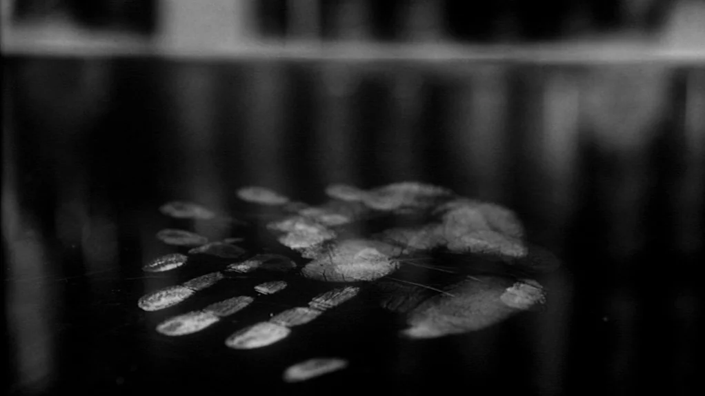 TwentyFourSeven (1997) movie still: closeup — A dark, smooth, and highly reflective surface shows clear residue of a handprint. The background is…