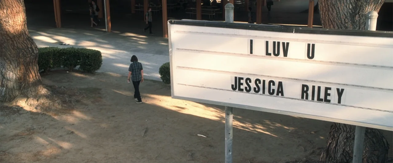 Crazy, Stupid, Love. (2011) movie still: wide — A high-angle view of a dirt school courtyard featuring a prominent white marquee sign. A lone…