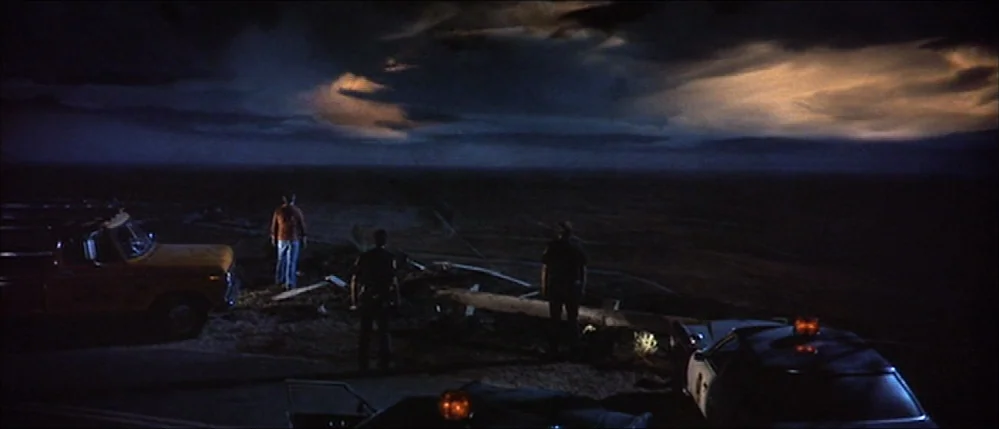 Close Encounters Of The Third Kind (1977) movie still: wide — A dark, expansive desert plateau at night with dramatic clouds illuminated by…