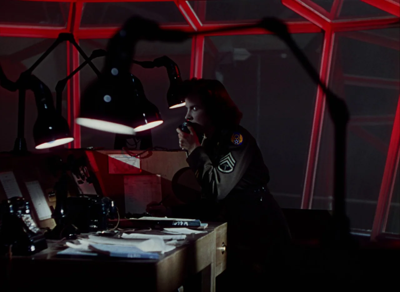 A Matter of Life and Death (1946) movie still: medium — A dark military tower features angular red metal beams and a cluttered wooden desk. A female…