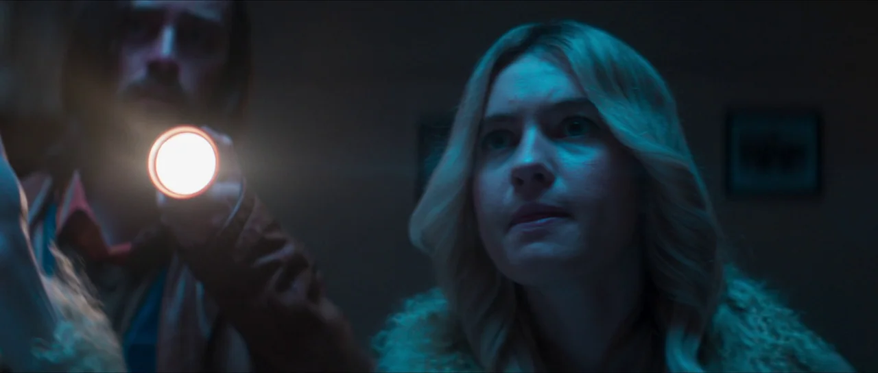 The Sacrifice Game (2023) movie still: medium — A dimly lit narrow space is illuminated by the harsh beam of a flashlight. A woman with blonde hair…