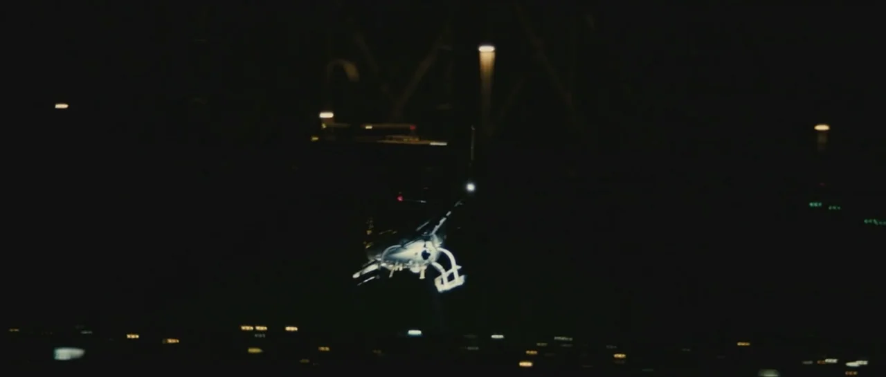 Contraband (2012) movie still: wide — A helicopter is airborne at night over a dark landscape with distant city lights. The aircraft is visible…