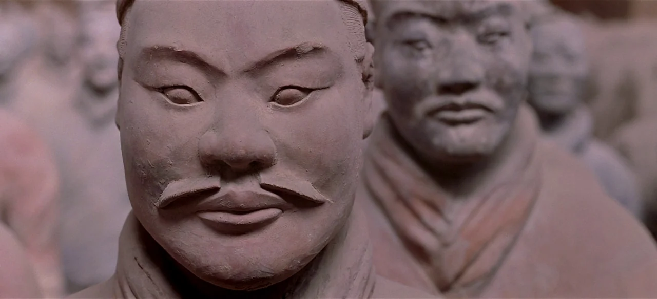 Baraka (1992) movie still: closeup — A collection of ancient Chinese terracotta soldiers stand closely together in a museum hall. A central clay…