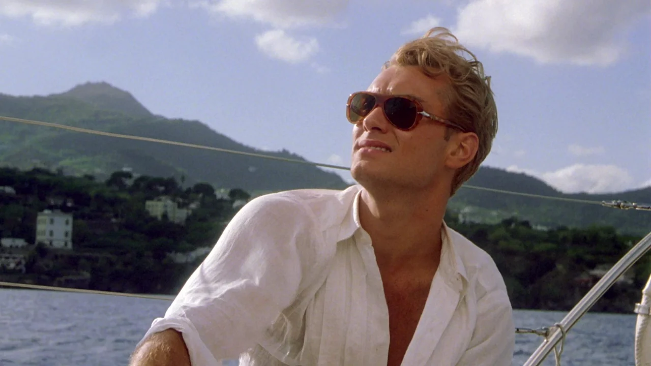 The Talented Mr. Ripley (1999) movie still: medium — A man sits on the deck of a sailboat with mountains in the background. The man gazes toward the…